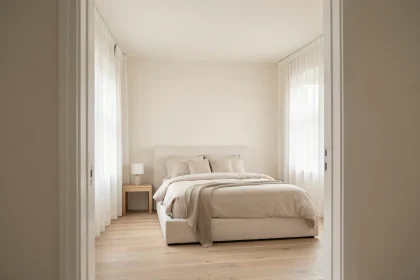 Chambre peinte en blanc cassé avec parquet clair et literie en lin neutre pour agrandir visuellement l'espace